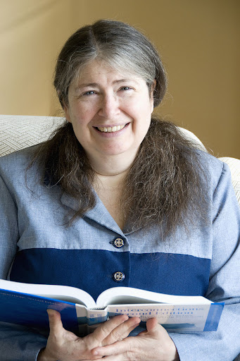 Radia Perlman in blue shirt holding a book