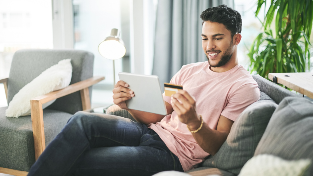 shot of young man using a credit card and digital tablet on the sofa at home