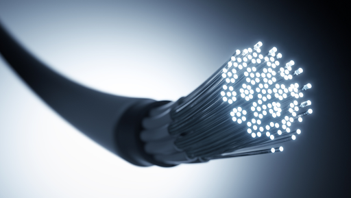 Close-up of a glowing fiber optic cable with numerous illuminated strands extending from the cut end, symbolizing high-speed data transmission and modern communication technology.