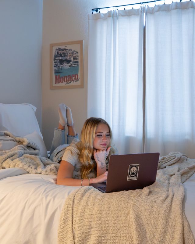 CSU student browsing on a laptop in her off-campus apartment bedroom