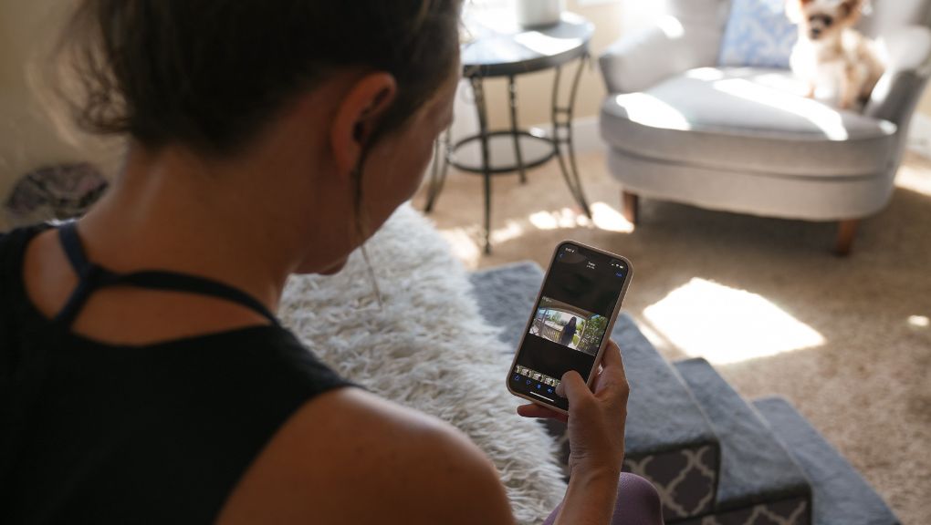 Woman using a mobile smart home app to monitor connected devices and security cameras at home while managing smart home automation internet requirements for reliable connectivity
